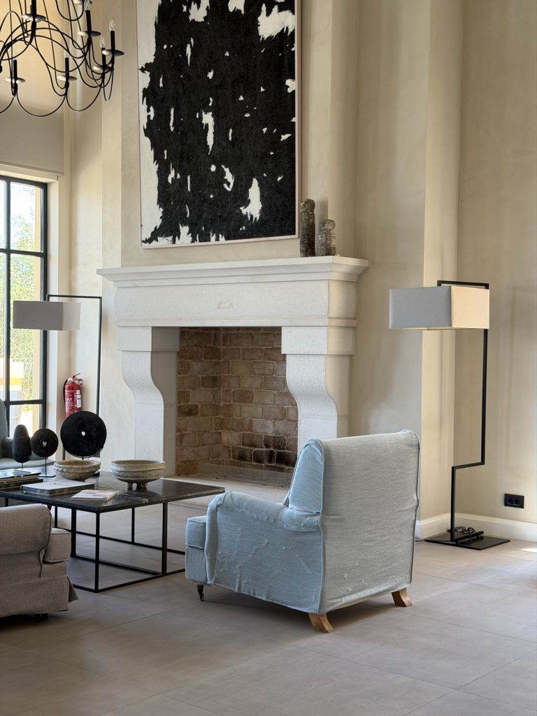 A designed lobby at the Nido, Mar-Bella Collection hotel in Corfu with a classic stone fireplace and a chandelier